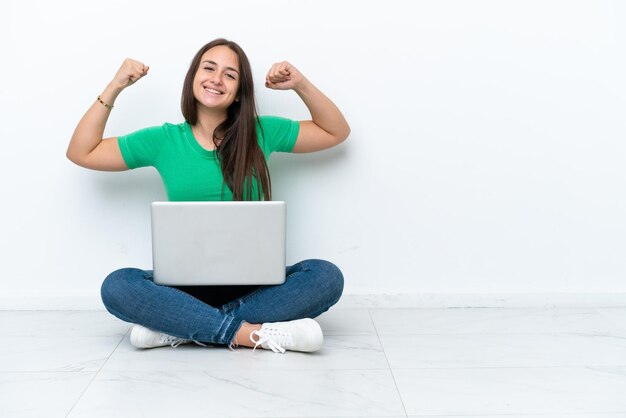 Joven ucraniana con una laptop sentada en el suelo haciendo un gesto fuerte