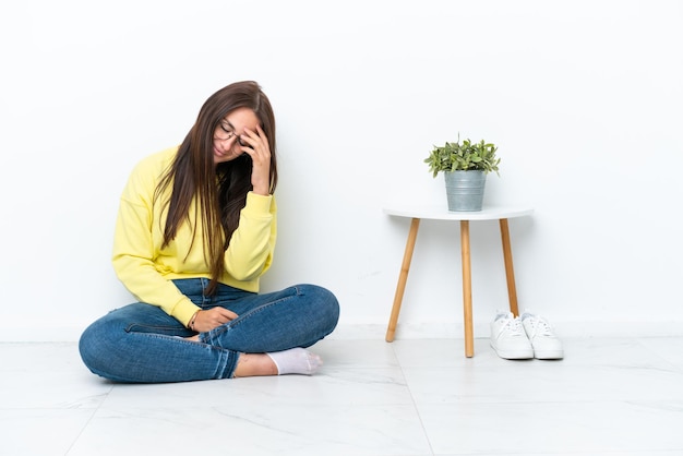 Foto joven ucraniana sentada en el piso de su casa aislada en una pared blanca riendo