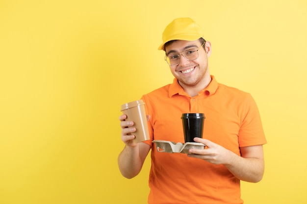 joven en uniforme naranja con tazas de café para llevar.