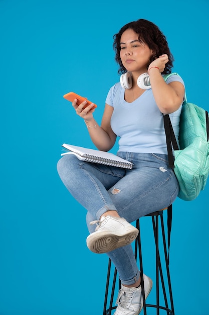 Joven universitaria triste y preocupada hablando por teléfono celular con altavoz