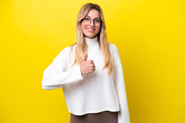 Joven uruguaya aislada de fondo amarillo dando un gesto de pulgar hacia arriba