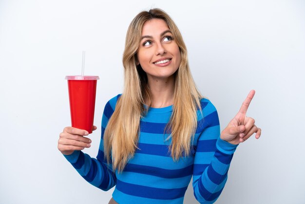 Joven uruguaya bebiendo soda aislada de fondo blanco señalando una gran idea