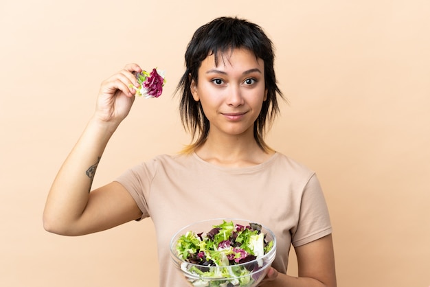 Foto joven uruguaya con ensalada en pared aislada