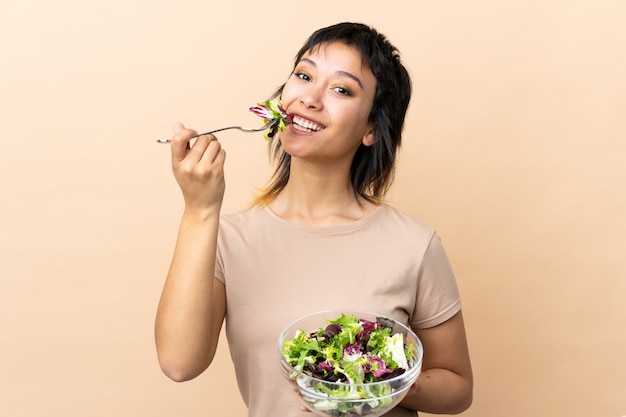 Joven uruguaya con ensalada sobre pared aislada