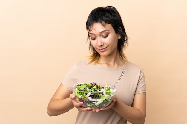 Joven uruguaya con ensalada sobre pared