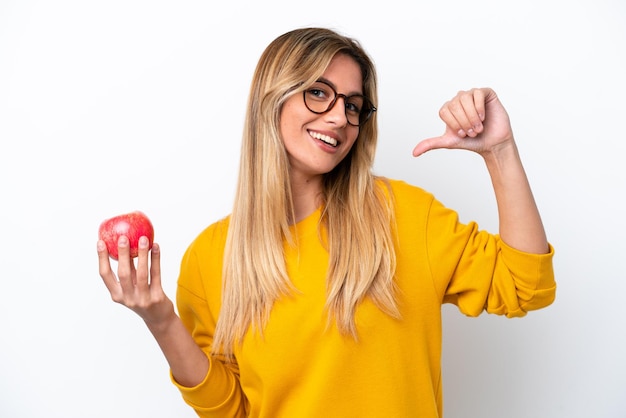 Joven uruguaya con una manzana aislada de fondo blanco orgullosa y satisfecha