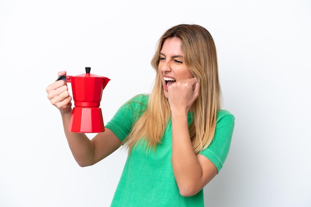 Joven uruguaya sosteniendo una cafetera aislada de fondo blanco celebrando una victoria