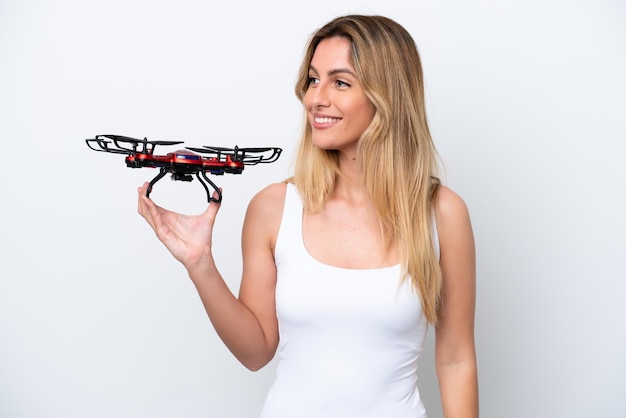 Joven uruguaya sosteniendo un dron aislado de fondo blanco mirando hacia un lado y sonriendo