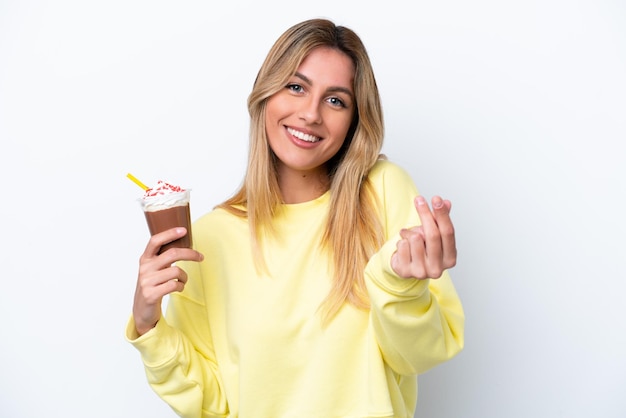 Joven uruguaya sosteniendo Frappuccino aislado de fondo blanco haciendo gesto de dinero