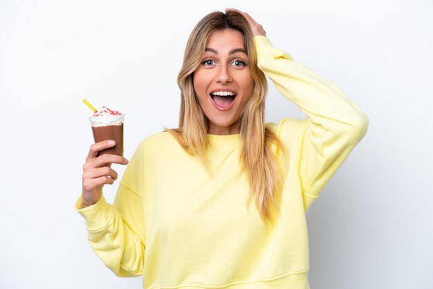 Joven uruguaya sosteniendo Frappuccino aislado sobre fondo blanco con expresión de sorpresa