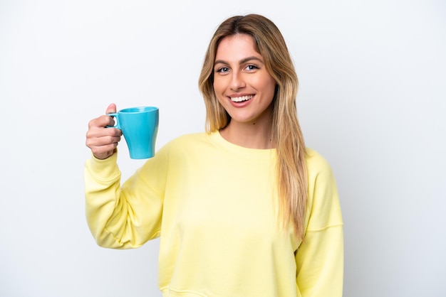 Joven uruguaya sosteniendo una taza de café aislada de fondo blanco sonriendo mucho