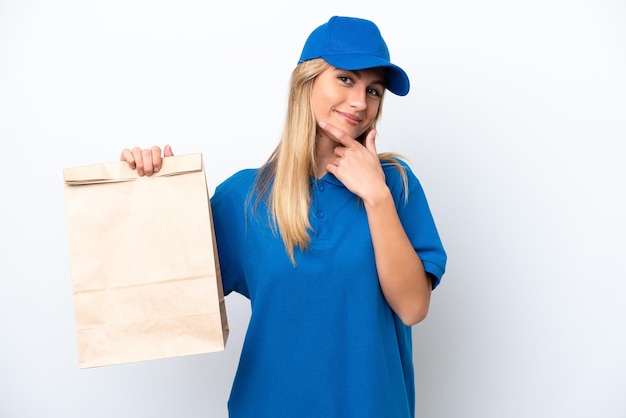 Joven uruguaya tomando una bolsa de comida para llevar aislada de fondo blanco feliz y sonriente