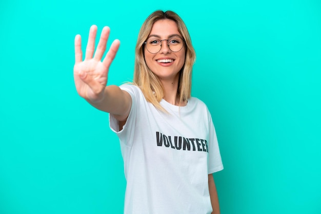 Joven uruguaya voluntaria aislada de fondo azul feliz y contando cuatro con los dedos