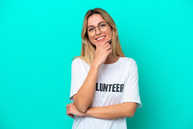 Joven uruguaya voluntaria aislada de fondo azul feliz y sonriente