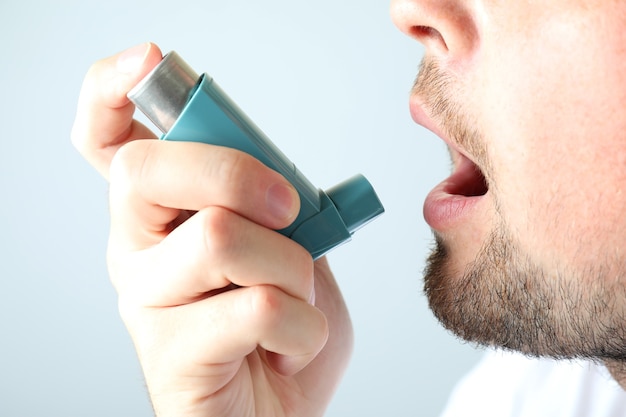 Foto joven usa inhalador para el asma, cerrar