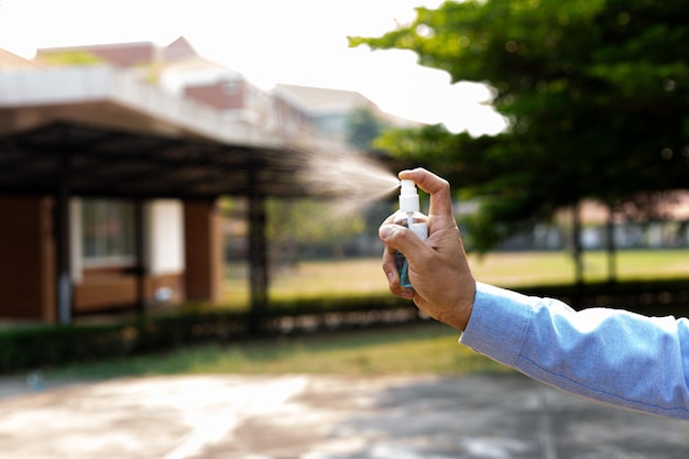 Foto un joven usa un spray de alcohol para deshacerse de bacterias y virus