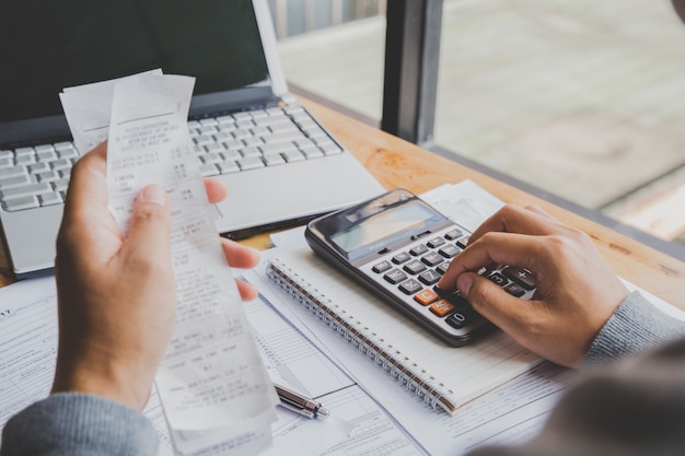 Joven usando la calculadora y calcular las facturas en la oficina en casa.