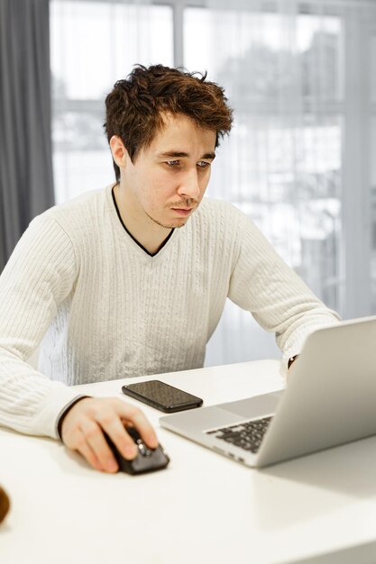 Joven usando una computadora portátil mientras está sentado en la mesa