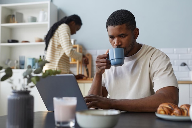 Joven usando laptop durante el desayuno