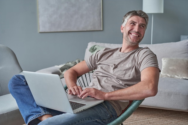 Joven usando laptop y sonriendo en casa