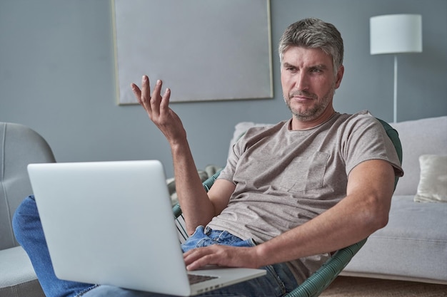 Joven usando laptop y sonriendo en casa