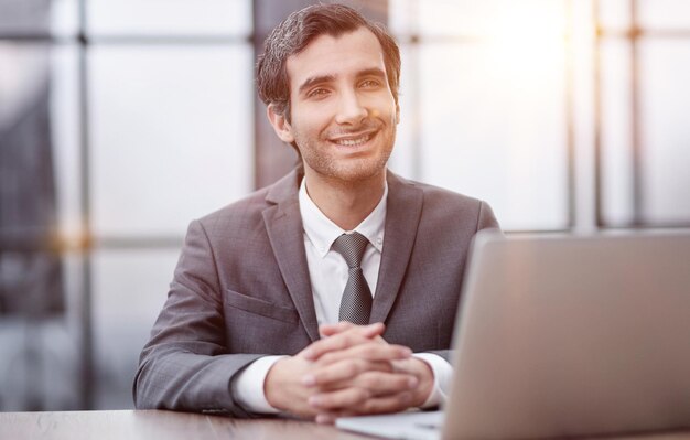 Joven usando laptop y sonriendo en la oficina