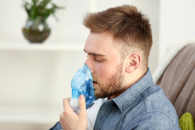 Foto joven usando nebulizador para asma y enfermedades respiratorias en casa