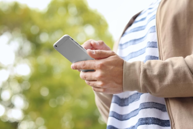 Joven usando su teléfono móvil al aire libre