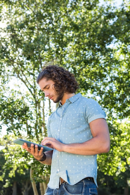 Joven usando tableta en el parque