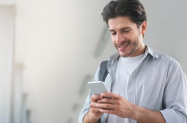 Joven usando un teléfono inteligente mientras espera su vuelo en el aeropuerto