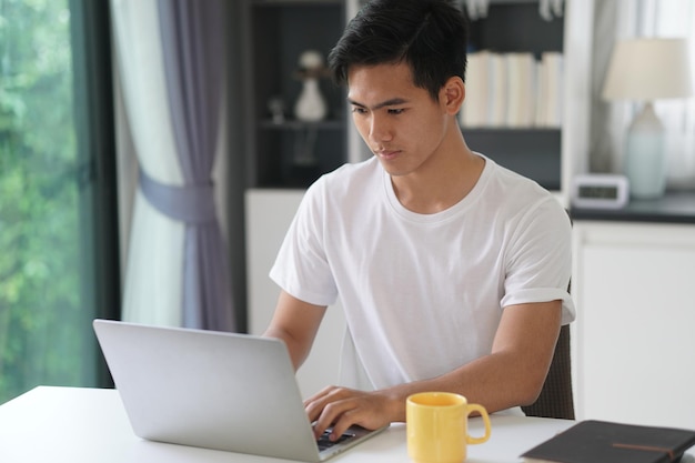 Joven usando el teléfono móvil mientras está sentado en la mesa
