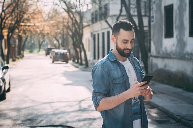 Foto joven usando el teléfono móvil mientras está de pie en la calle