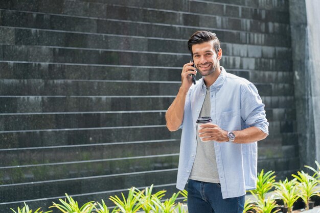 Foto joven usando el teléfono móvil mientras está de pie contra la pared