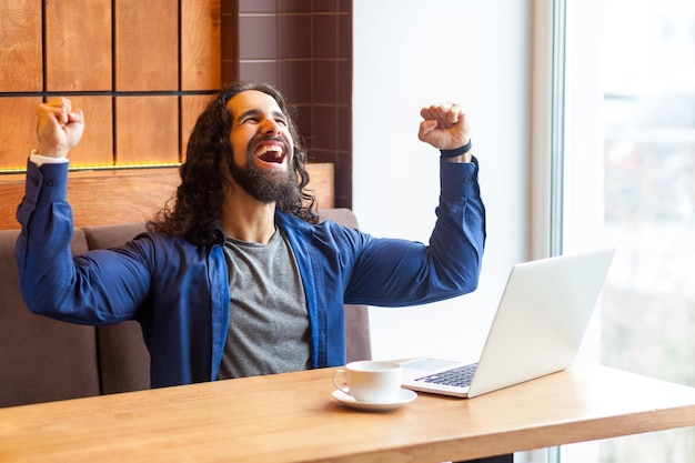 Foto joven usando el teléfono móvil mientras está sentado en la mesa