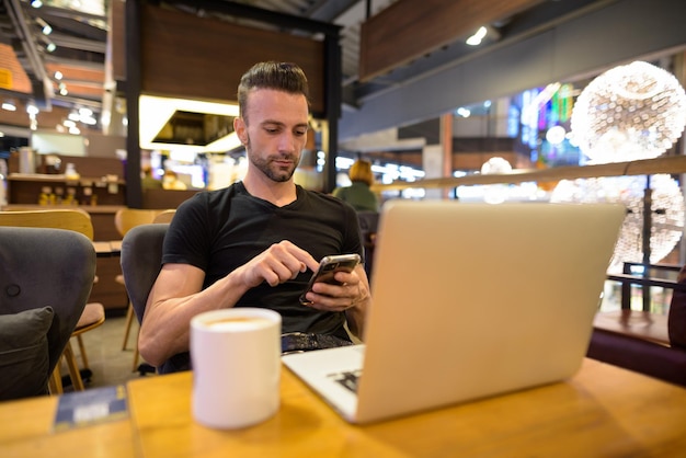 Foto joven usando el teléfono móvil mientras está sentado en la mesa