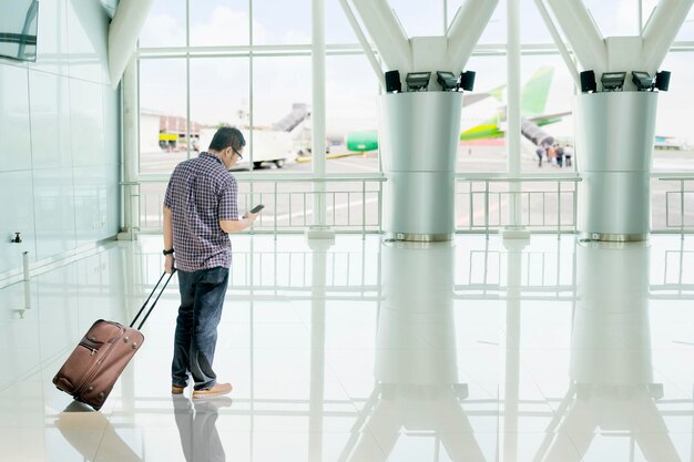 Joven usando un teléfono en la terminal del aeropuerto