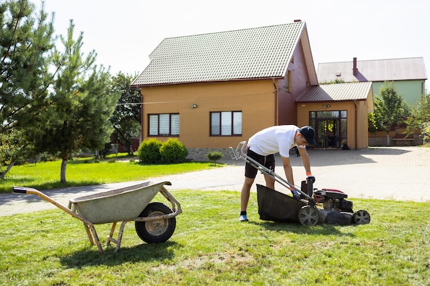 Joven vaciando el recogedor de césped de la cortadora de césped