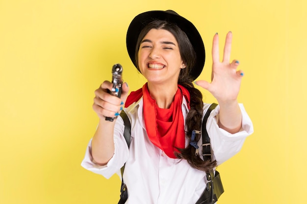 Una joven vaquera sonriente apunta con una pistola a la cámara Foto de alta calidad