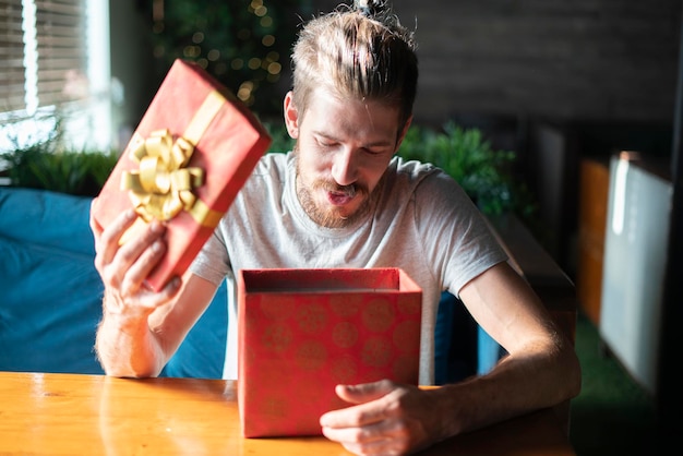 Un joven varón abre una caja de regalo roja en Navidad