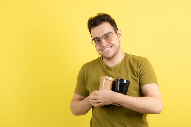 joven en vasos sosteniendo dos tazas de café.