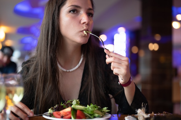 Joven vegetariana comiendo ensalada en el restaurante.