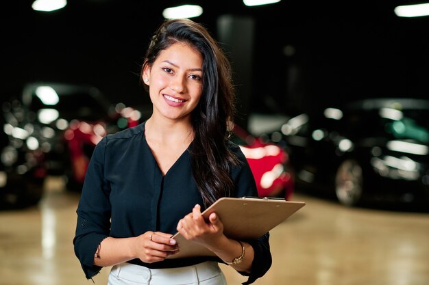 joven vendedora latina vendiendo coches de lujo