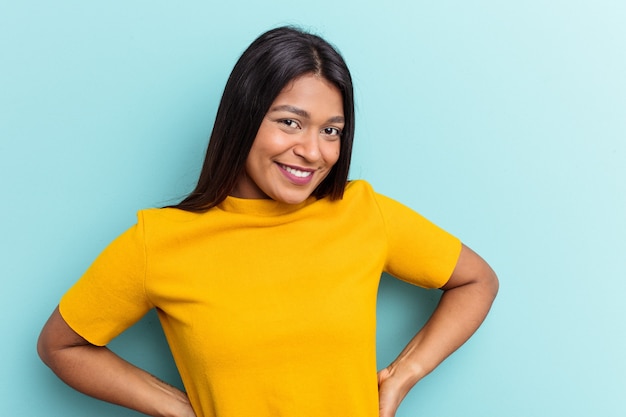 Joven venezolana aislada sobre fondo azul feliz, sonriente y alegre.