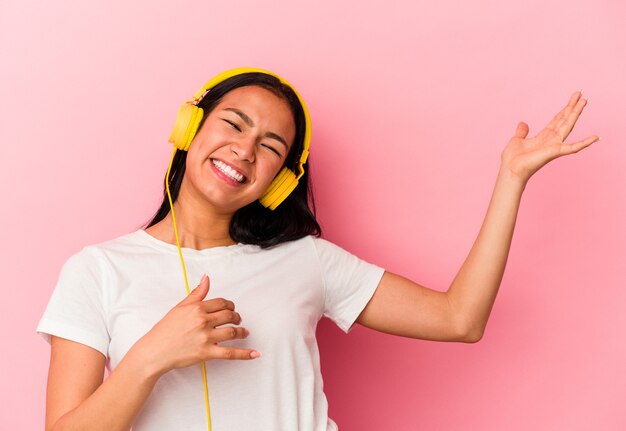 Joven venezolana escuchando música aislada en pared rosa