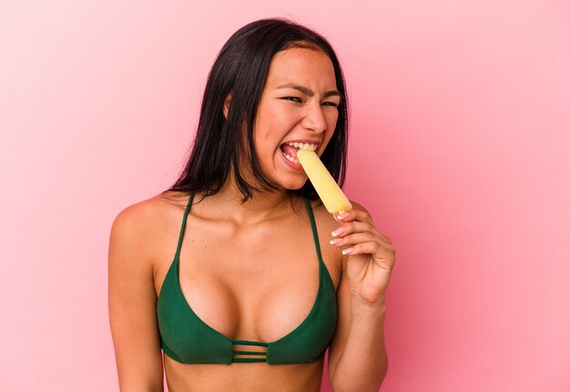 Joven venezolana sosteniendo un helado aislado de fondo rosa