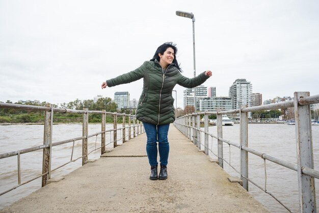 joven venezolana de vacaciones en Argentina feliz bailando en el muelle del puerto de Olivos