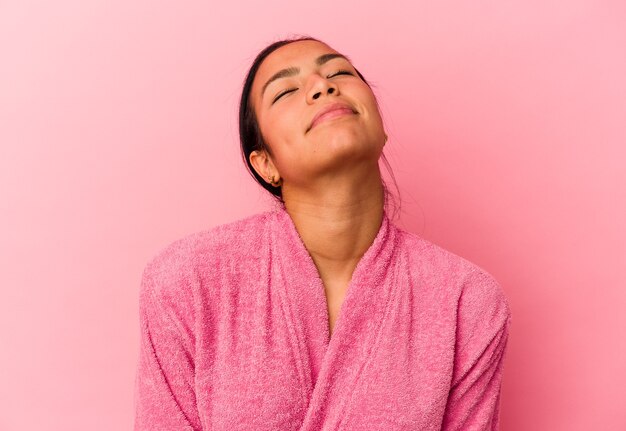 Joven venezolana vistiendo una bata de baño aislada sobre fondo rosa soñando con lograr metas y propósitos