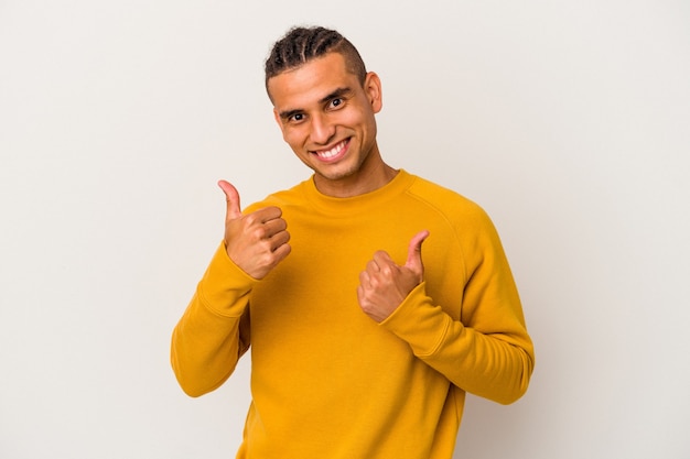 Joven venezolano aislado sobre fondo blanco levantando ambos pulgares, sonriente y confiado.