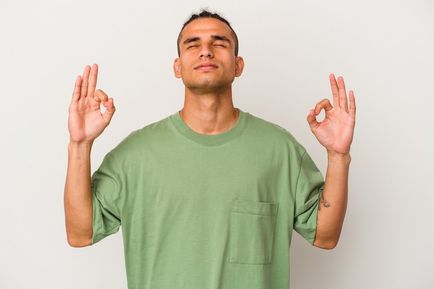 Joven venezolano aislado sobre fondo blanco se relaja después de un duro día de trabajo, ella está realizando yoga.