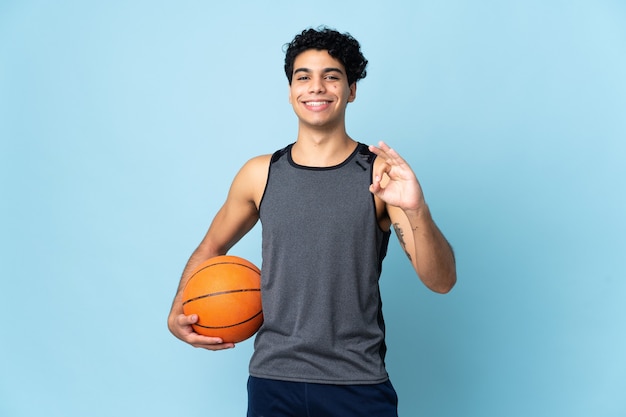 Foto joven venezolano en azul jugando baloncesto y haciendo el signo de ok